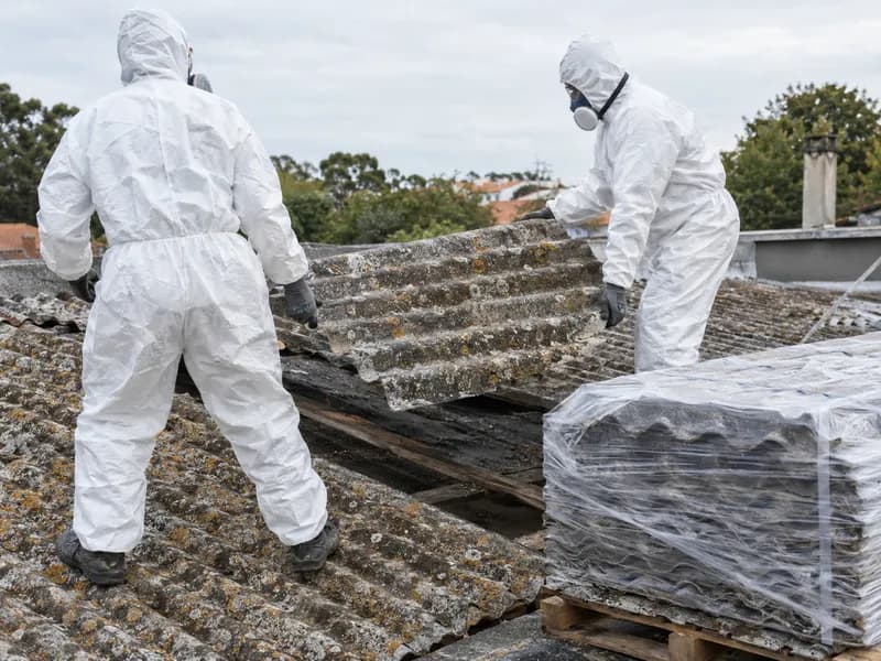 Trabalhadores com fatos de proteção a remover chapas antigas de fibrocimento